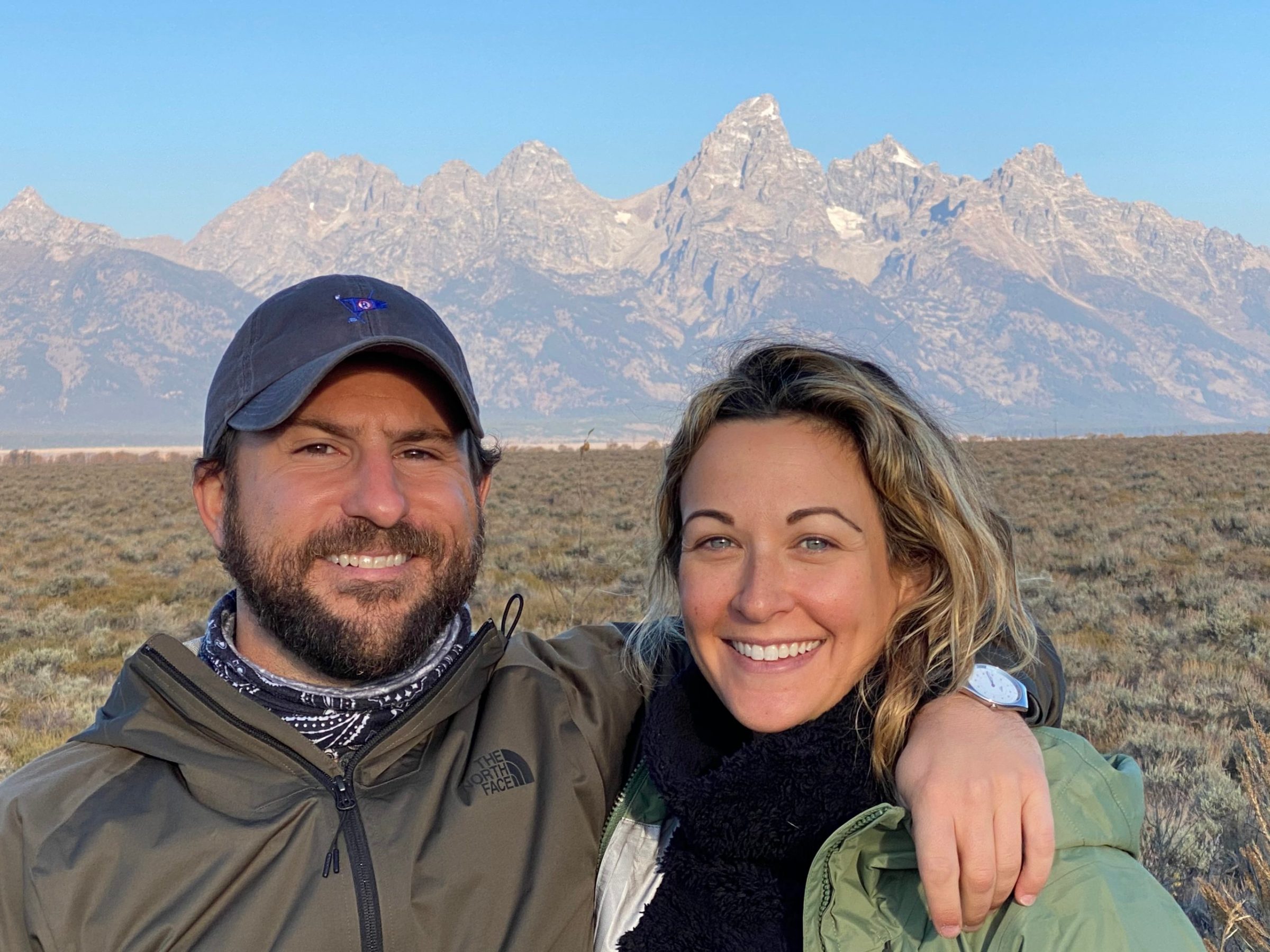 a man and a woman posing in front of a mountain