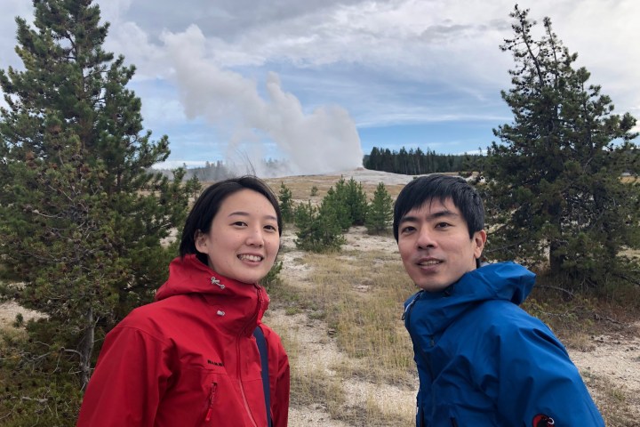 a man and a woman standing in front of a tree