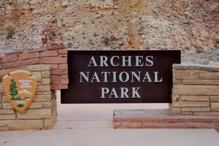 a sign on a wooden bench sitting in front of a brick building