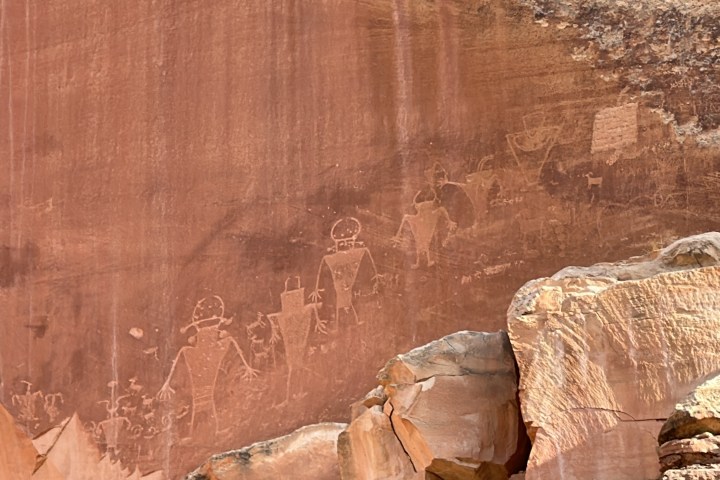 Ancient petroglyphs on a rocky surface, depicting human and animal figures.