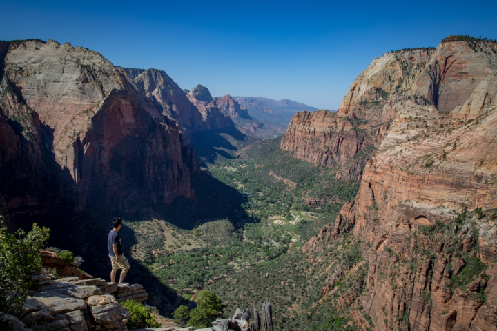 a person standing on a rocky hill with Zion National Park in the background