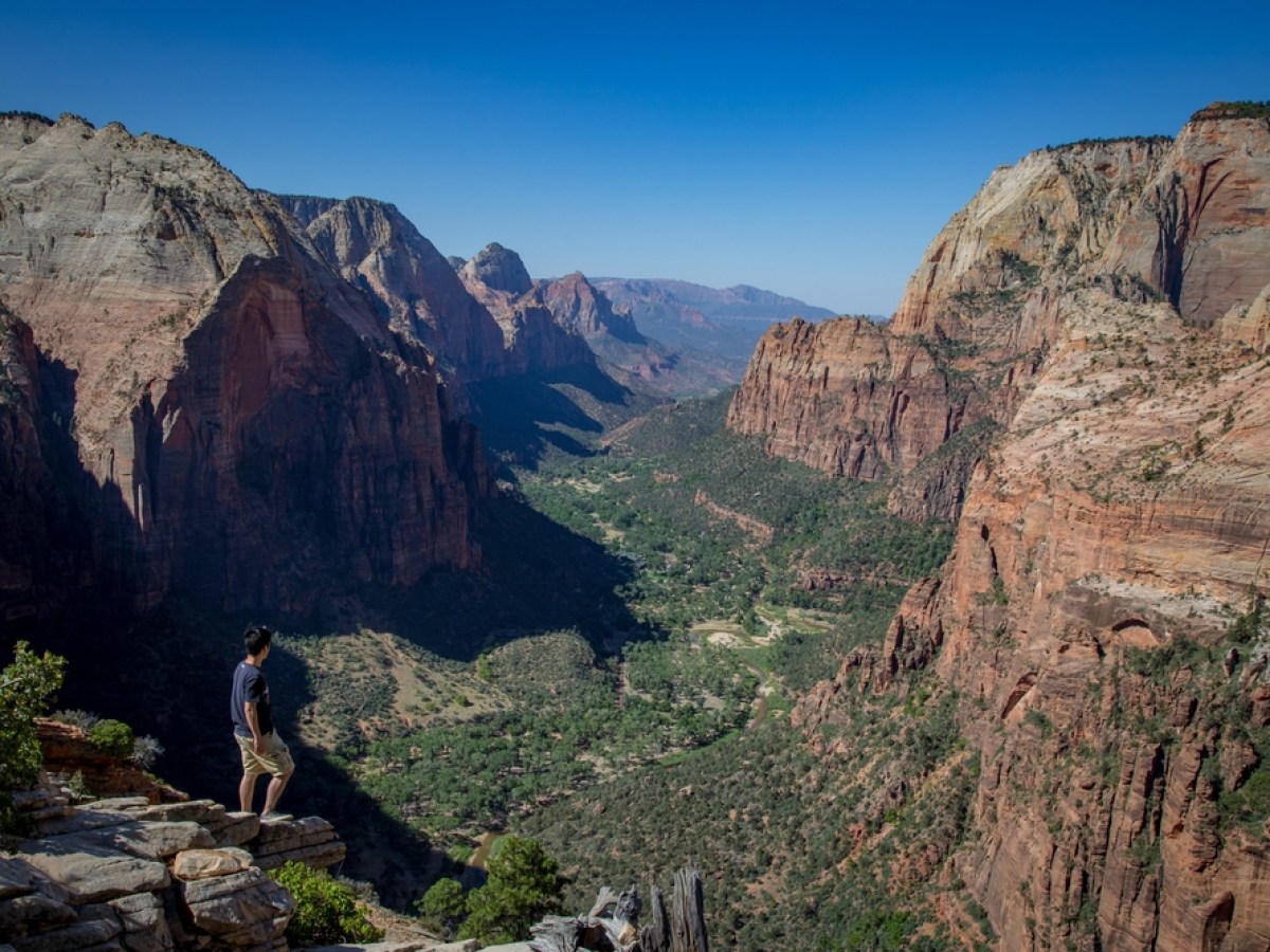 a person standing on a rocky hill with Zion National Park in the background