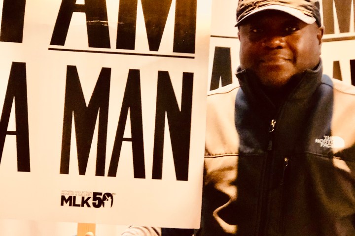 Person holding 'I AM A MAN' sign with similar signs in the background.