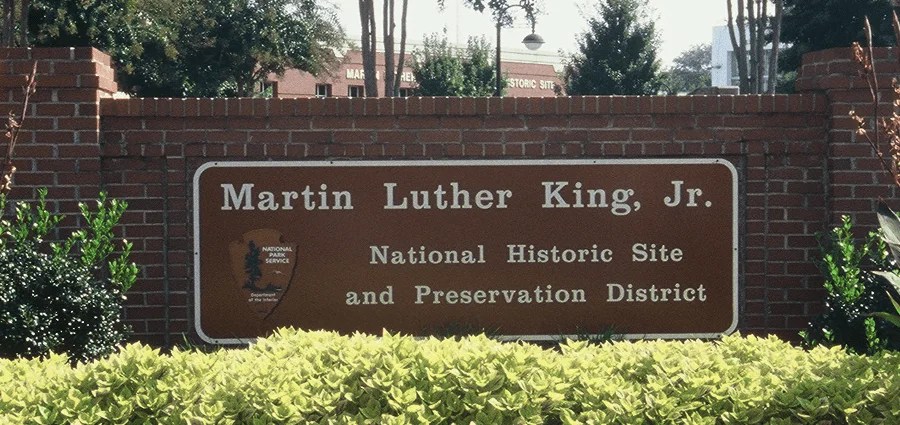 Brick sign for Martin Luther King Jr. National Historic Site with plants in front.