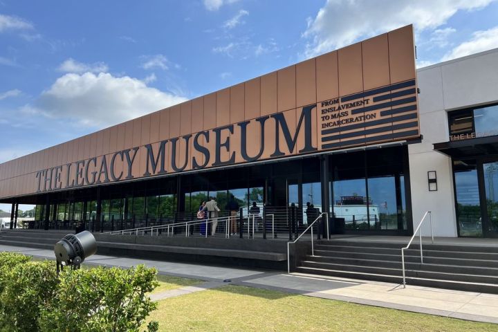 Exterior of The Legacy Museum with sign, stairs, and people entering.