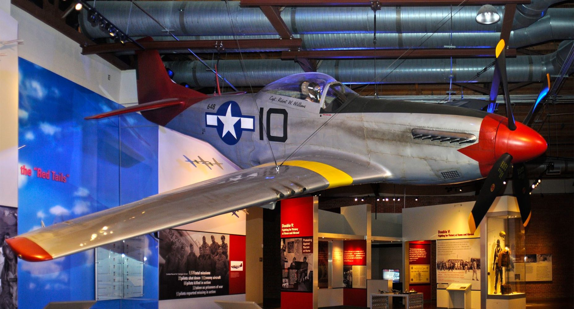 Vintage fighter plane suspended in a museum exhibit with informational displays.